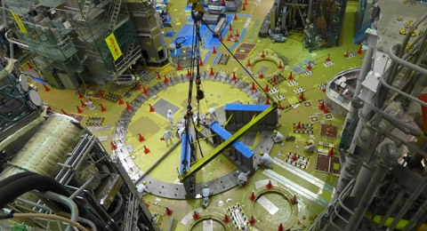 Des ouvriers lors du montage des premières parties de la structure portante du cryostat. Une fois assemblée, celle-ci mesure 12 mètres de diamètre sur 3 mètres de haut.