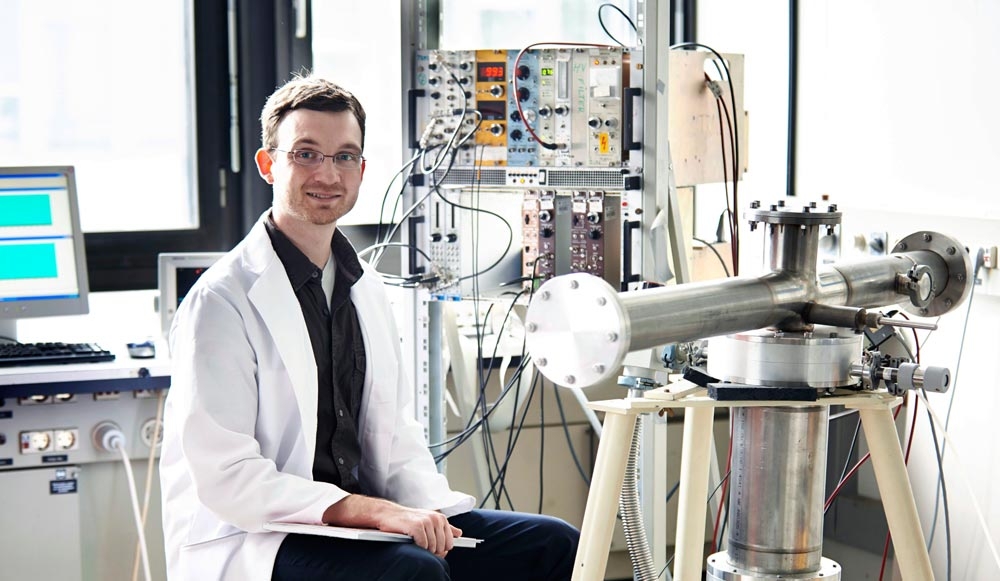 Nils Haag neben seinem Doppeldetektor im Labor, mit dem er das Antineutrino-Spektrum von U-238 bestimmen konnte. Die beiden Detektoren befinden sich im unteren Teil des Aufbaus.