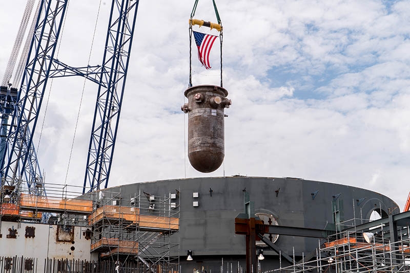 Mit Hilfe eines Schwerlast-Drehkrans wird der Reaktordruckbehälter an seinen Platz im Reaktorgebäude der AP1000-Einheit Virgil C. Summer-2 gesetzt.